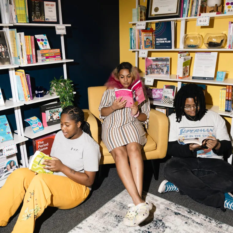 Group of three teenagers reading in a library